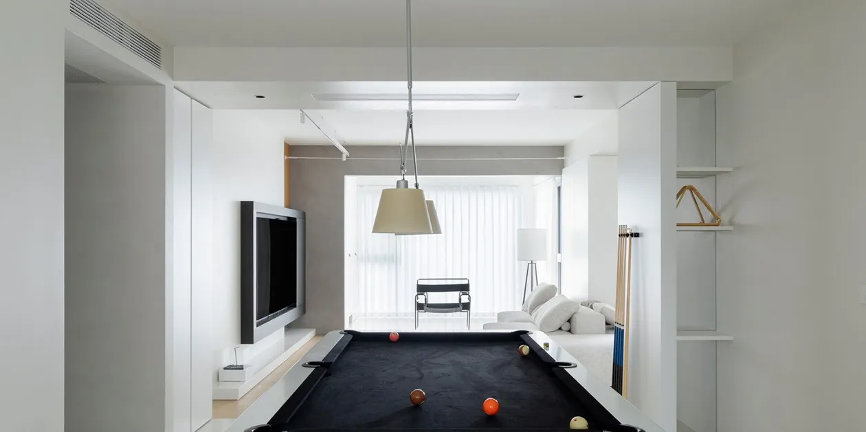 A modern living room with white walls, a black pool table, and a flat-screen TV.
