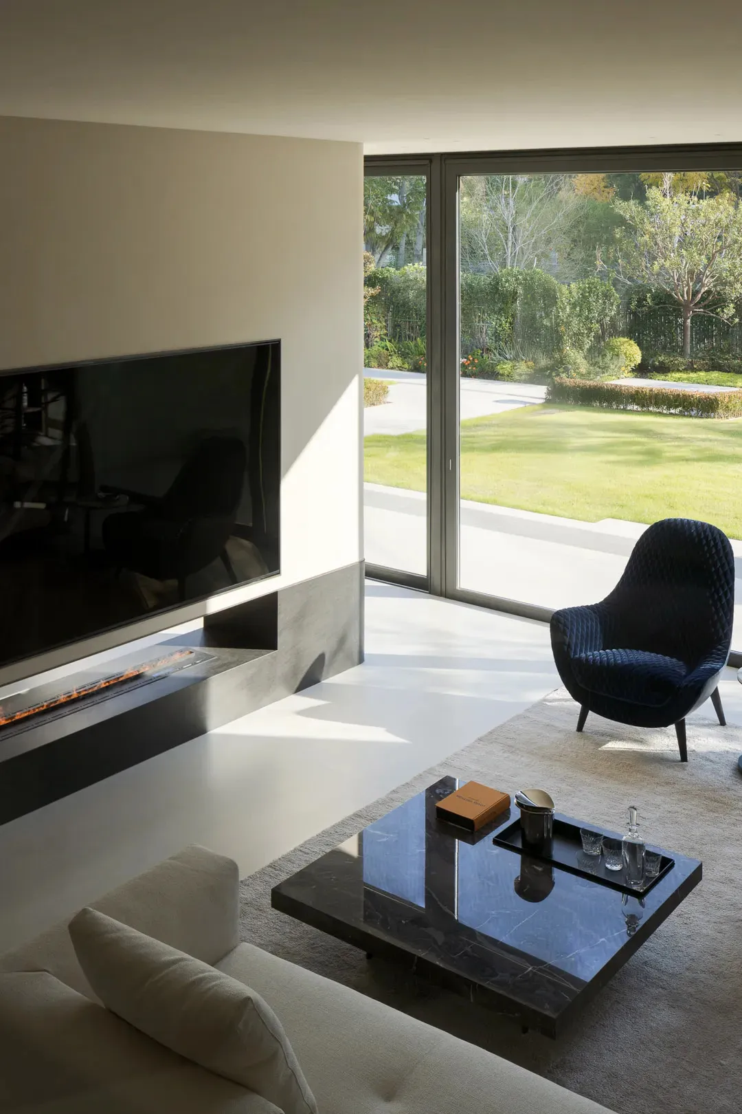 現代極簡客廳,搭配大理石咖啡桌、混凝土壁爐,以及通往花園的玻璃拉門。