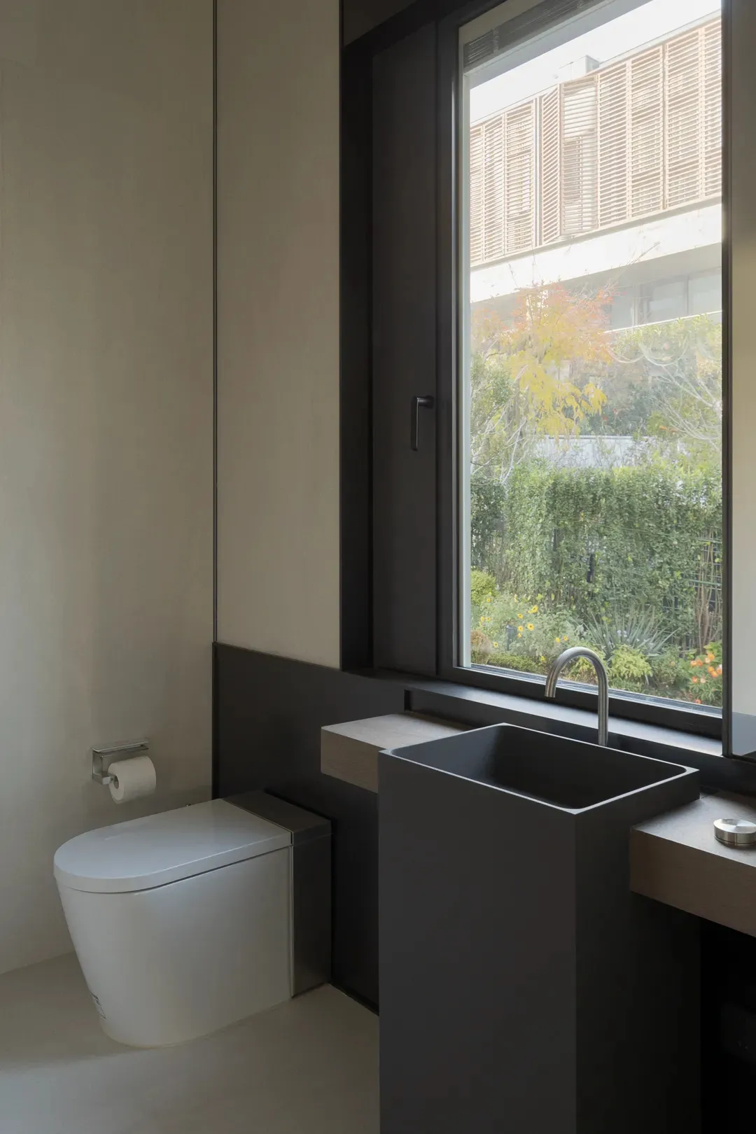 Modern bathroom with minimalist design, featuring a sleek, black rectangular sink and a white toilet, complemented by a large