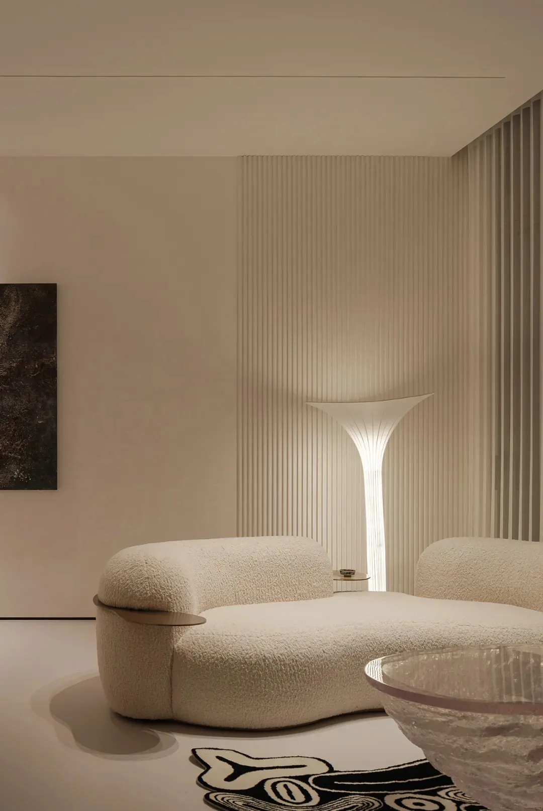 Modern minimalist living room featuring a soft-textured sofa and a tall, elegant lamp
