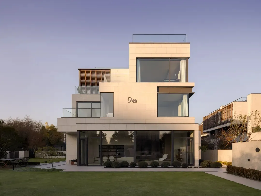 Modern house with concrete exterior and glass windows, featuring a roof balcony.