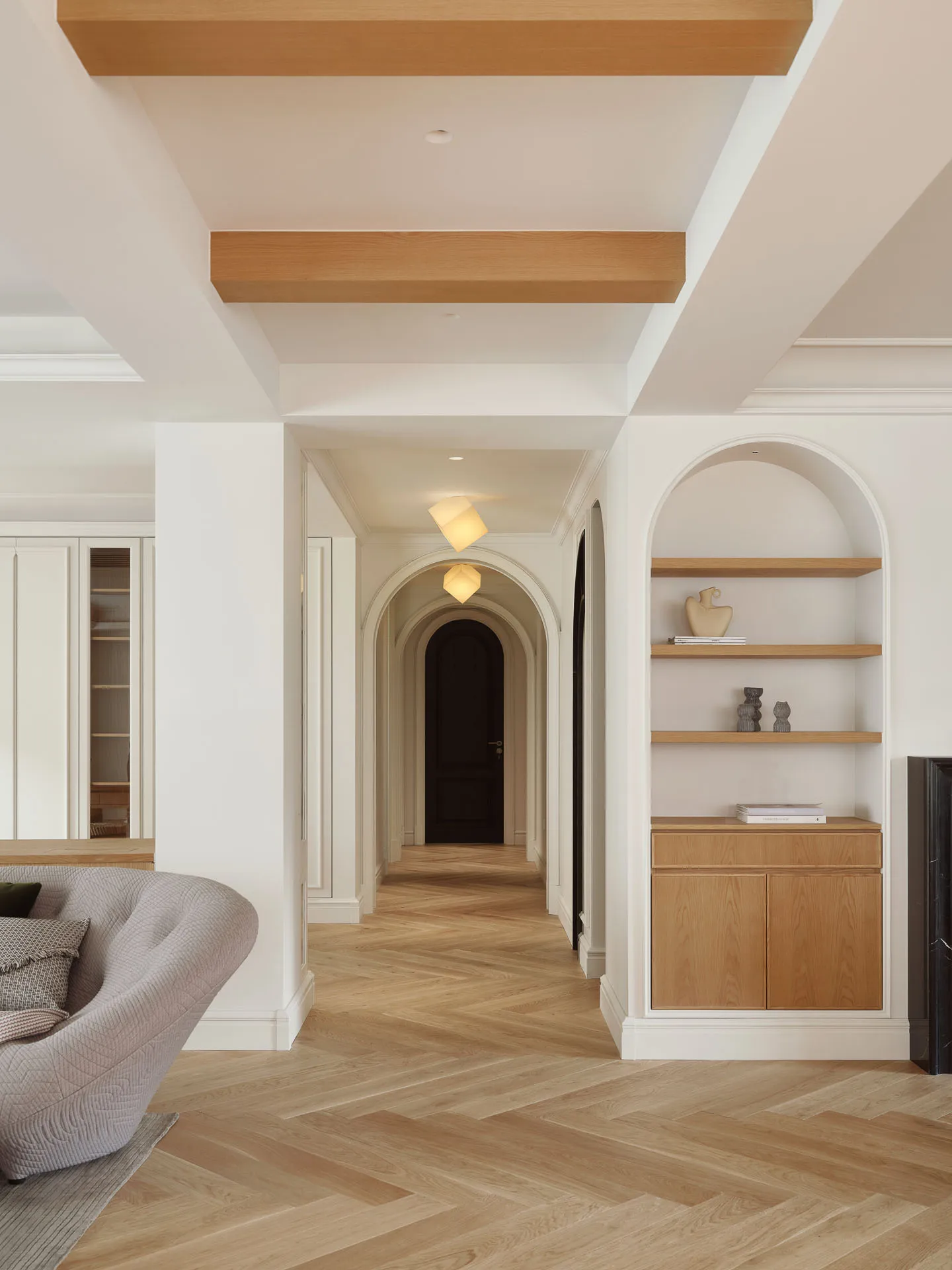 Modern minimalistic living room with white walls, wooden furniture, and herringbone floor pattern.