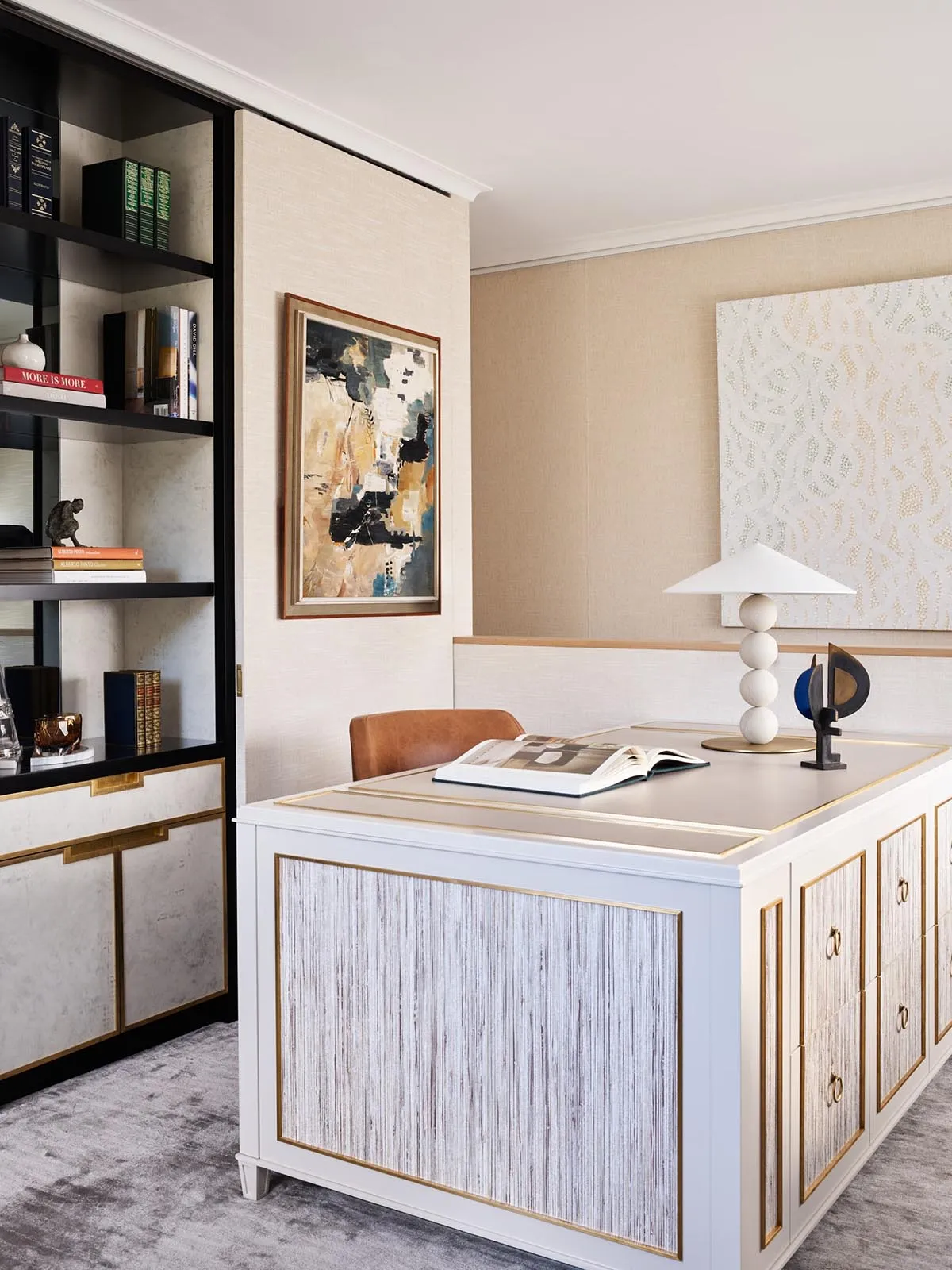 A modern home office featuring a white desk, abstract art, and leather chair.
