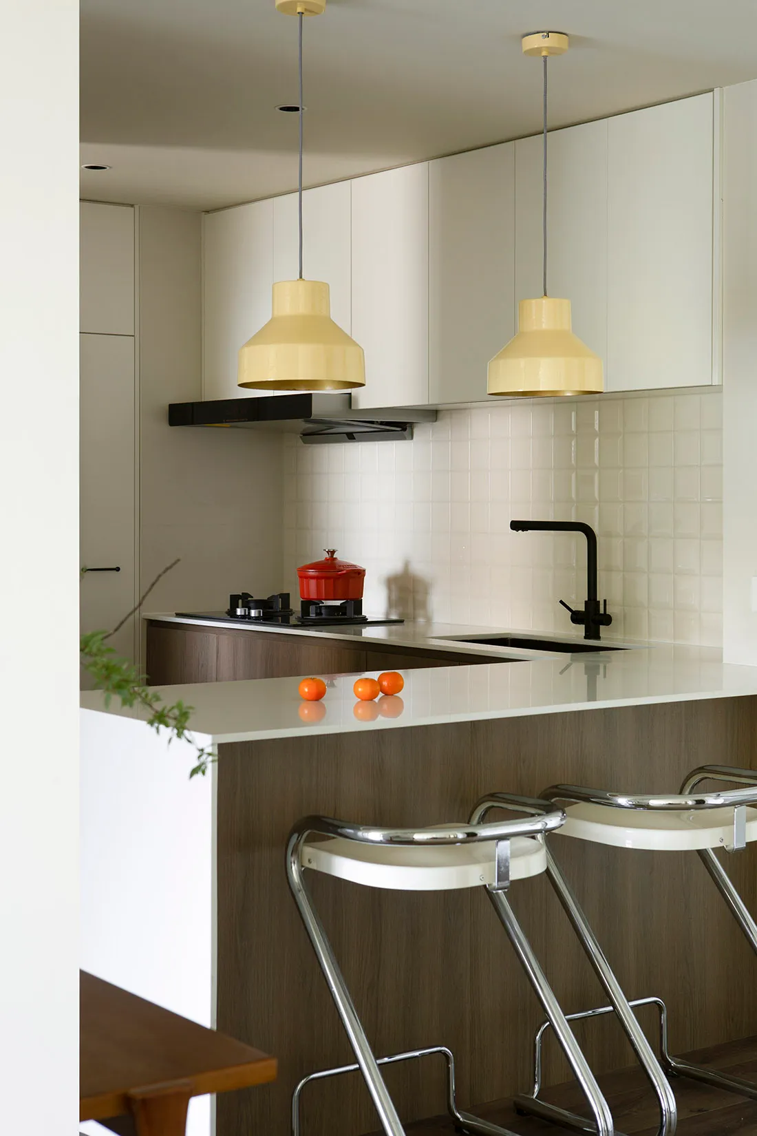 A spacious, modern kitchen with white-painted walls and ceiling, wooden flooring, and glass elements.