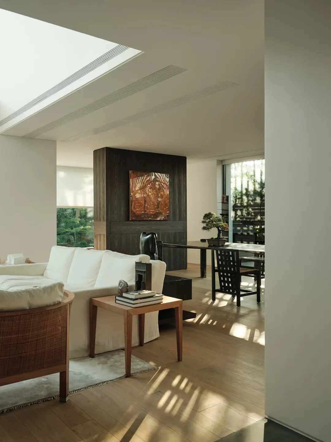 Modern living room featuring hardwood flooring, white sofas, and wooden side table with books and decorative items.