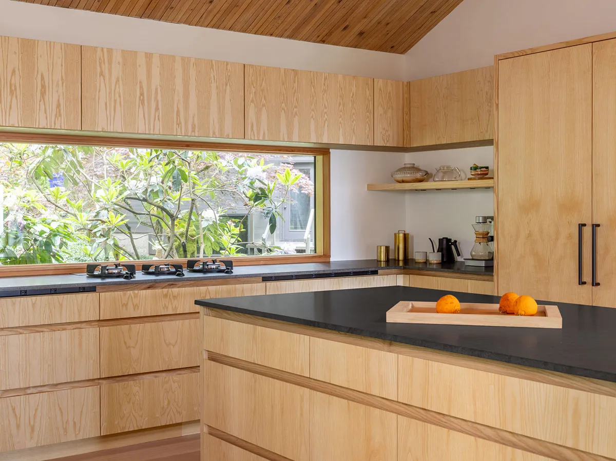 A modern minimalist kitchen with wooden cabinets and a black countertop.