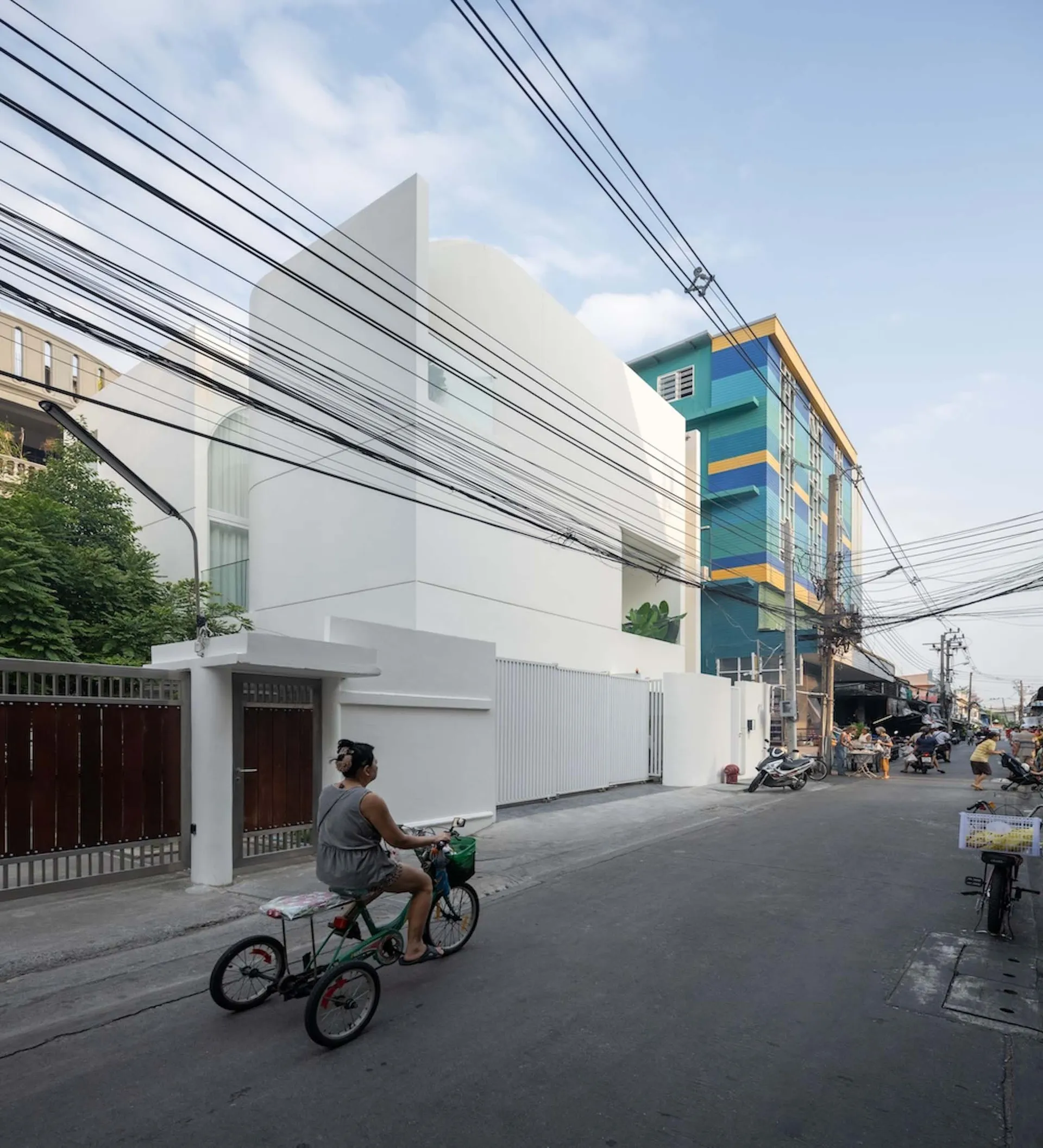 Modern building with white concrete exterior, street view with bicycles and power lines