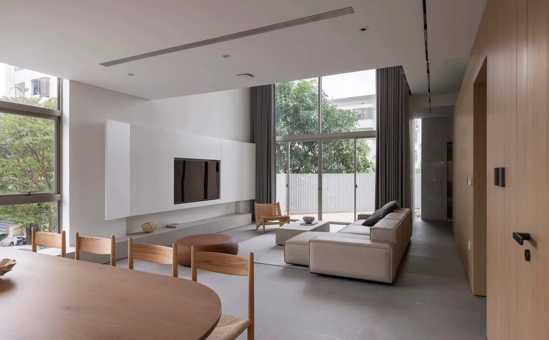 Modern living room with concrete walls, minimalist furniture, and large windows.