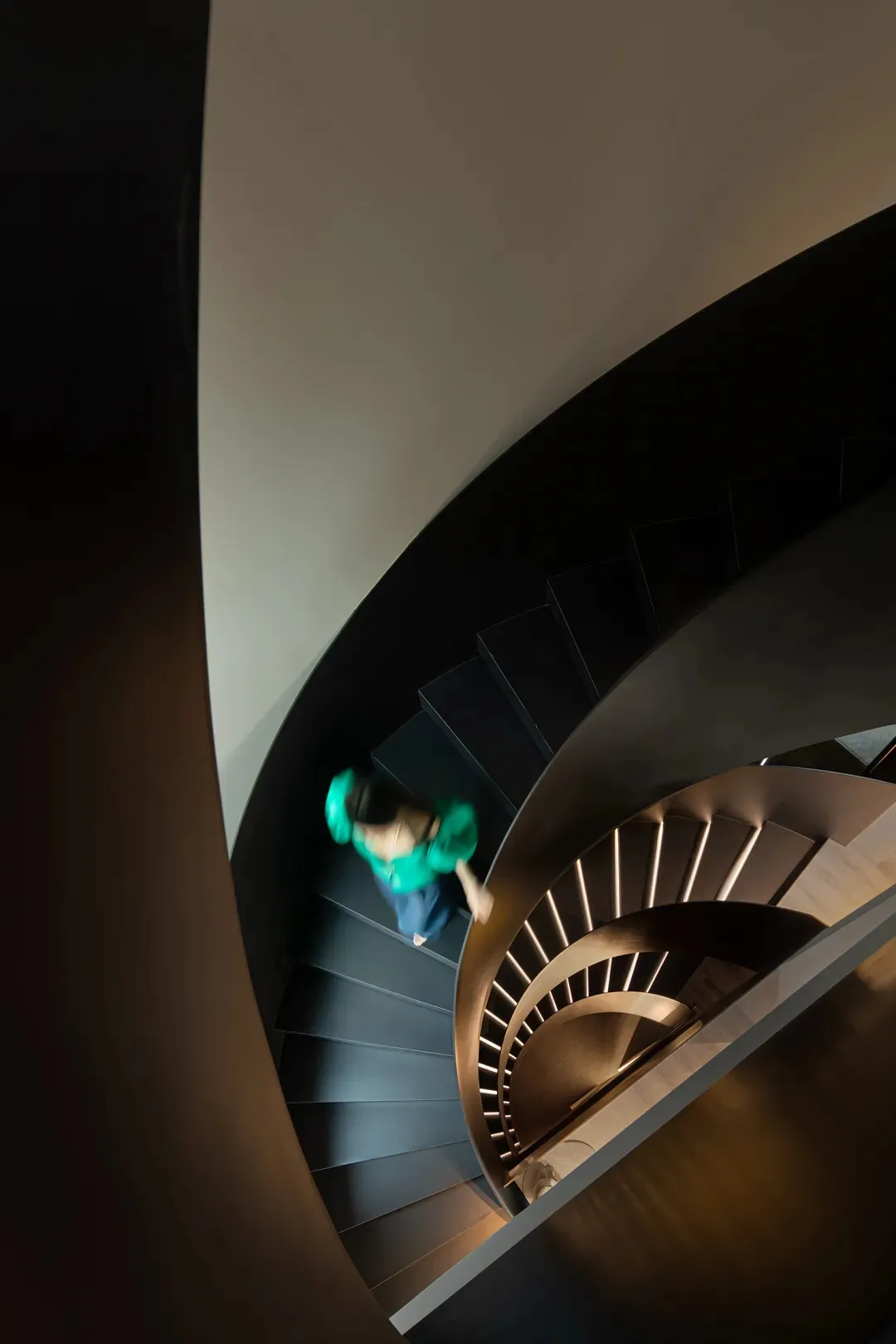 A person climbing a modern, curved staircase made of metal.