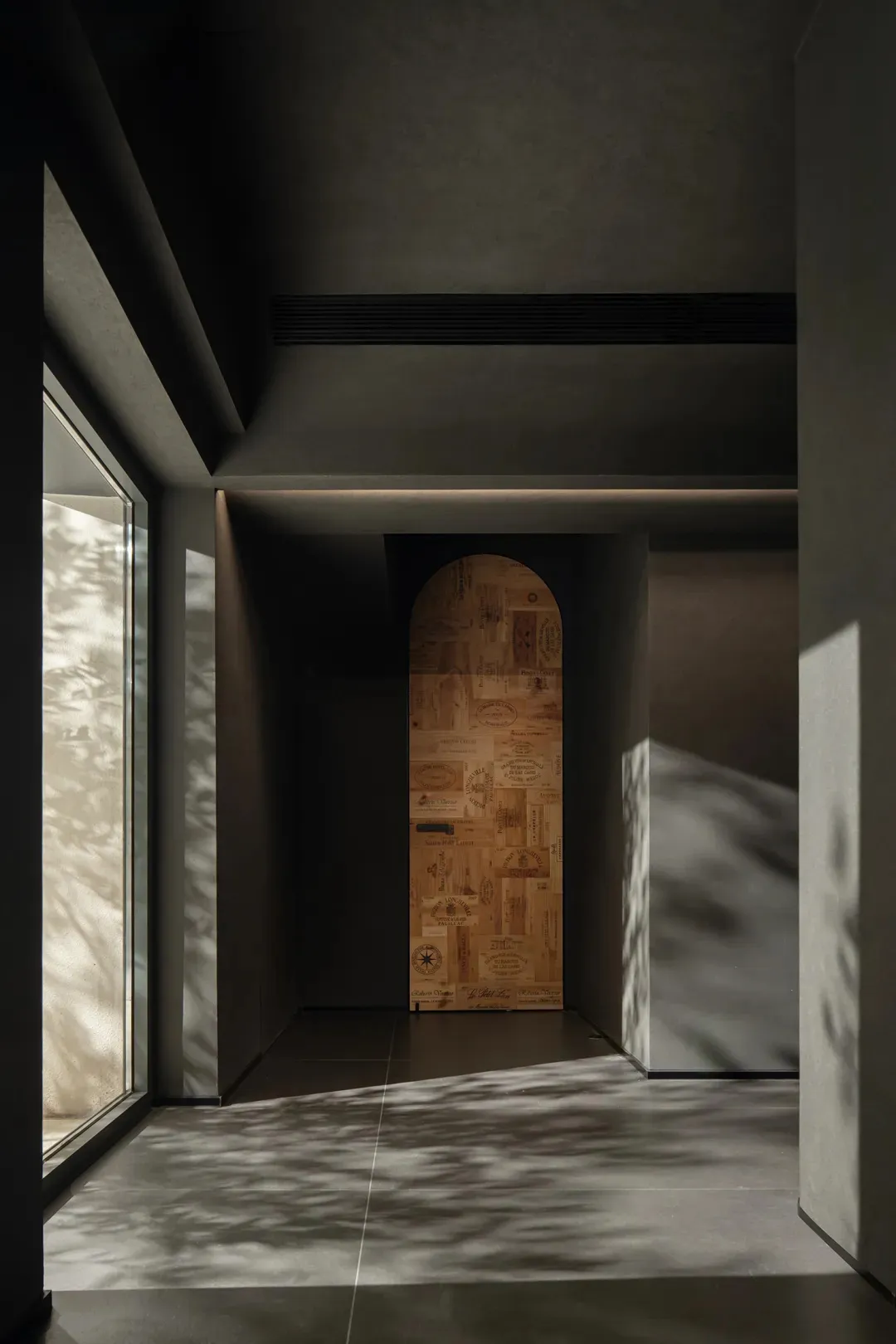 A modern doorway with industrial design elements, featuring an arched wooden door with textural patterns.