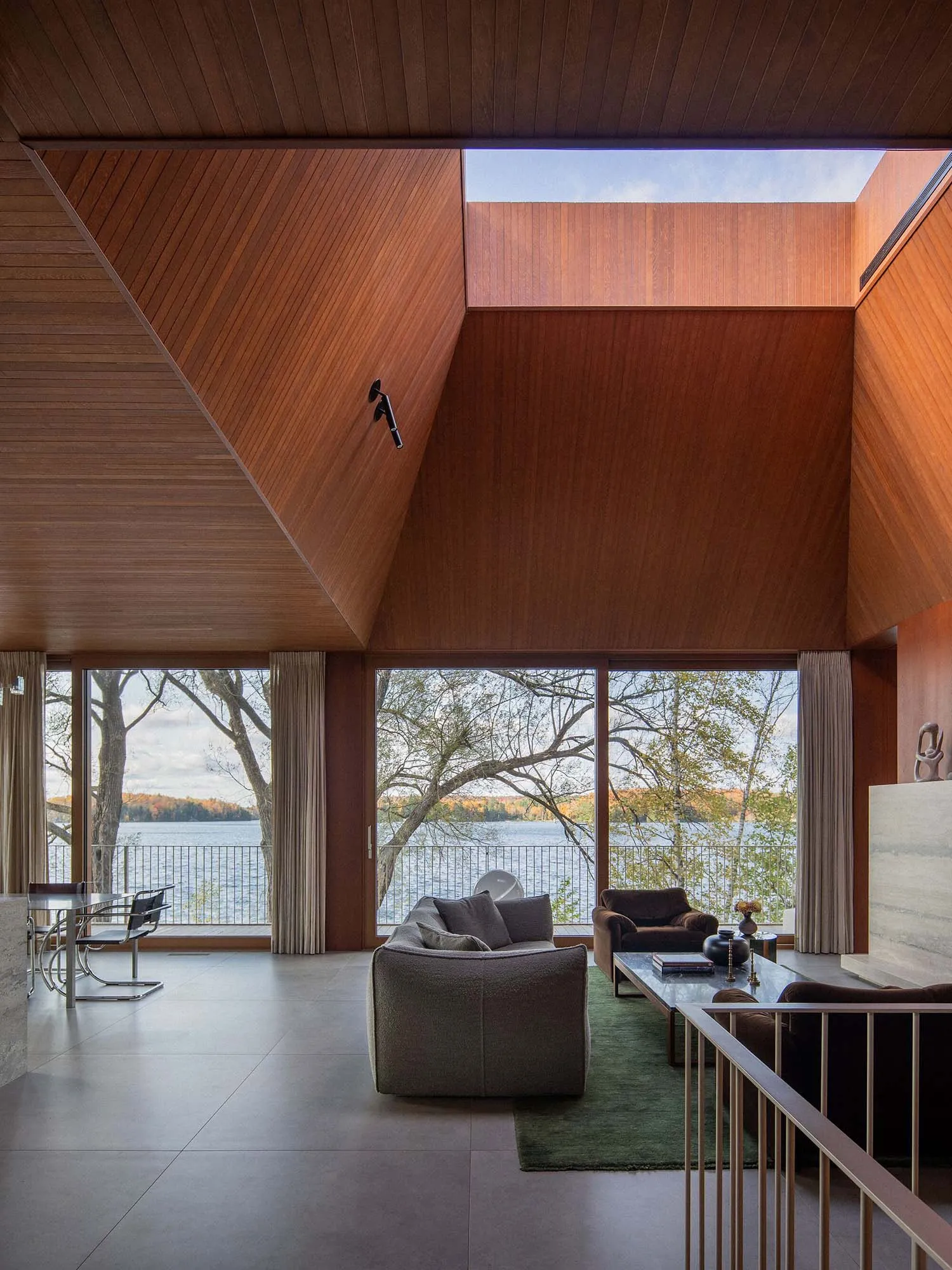 Modern living room with furniture and large windows overlooking a lake.