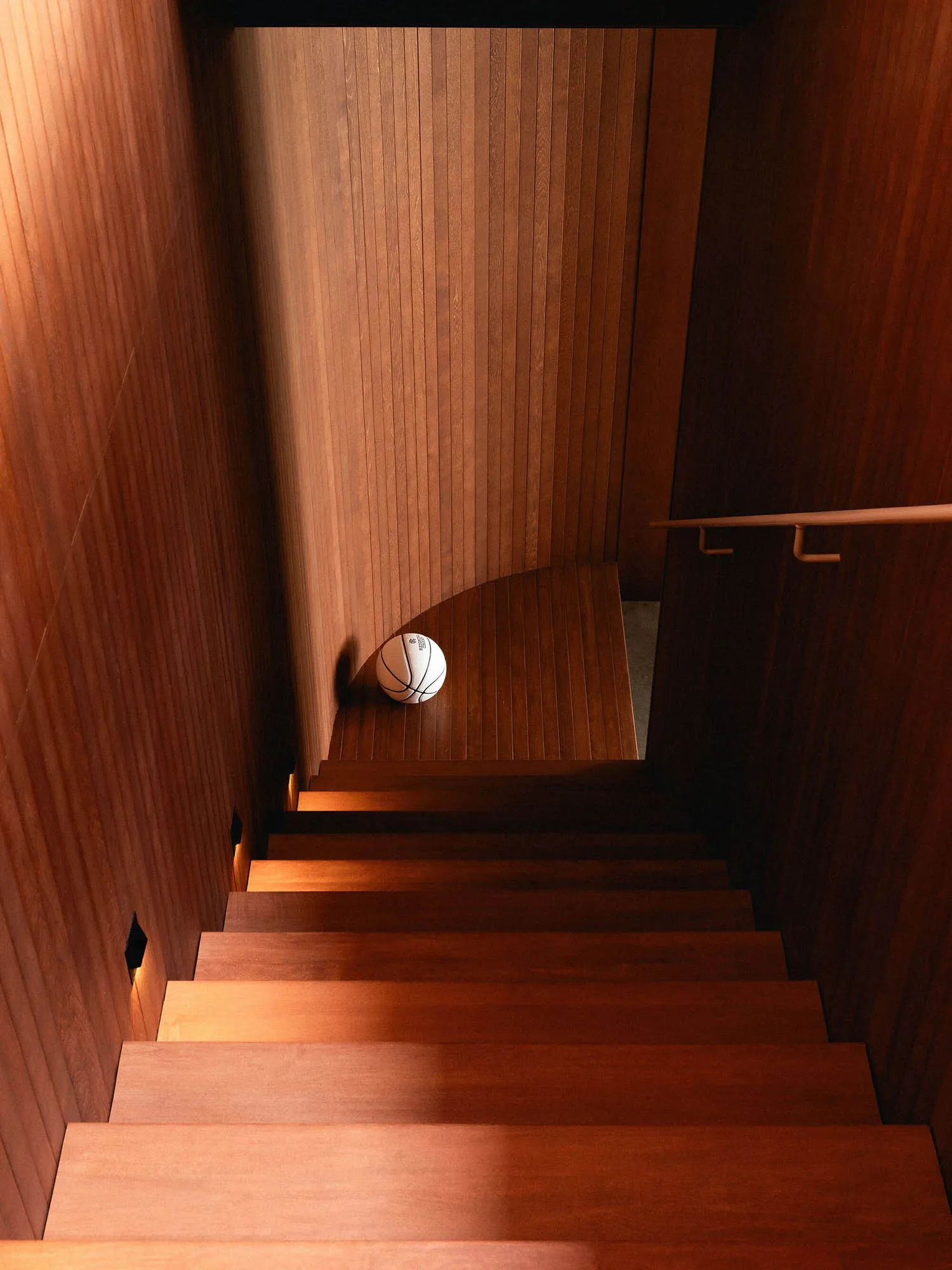 A wooden staircase with a basketball ball on the step.