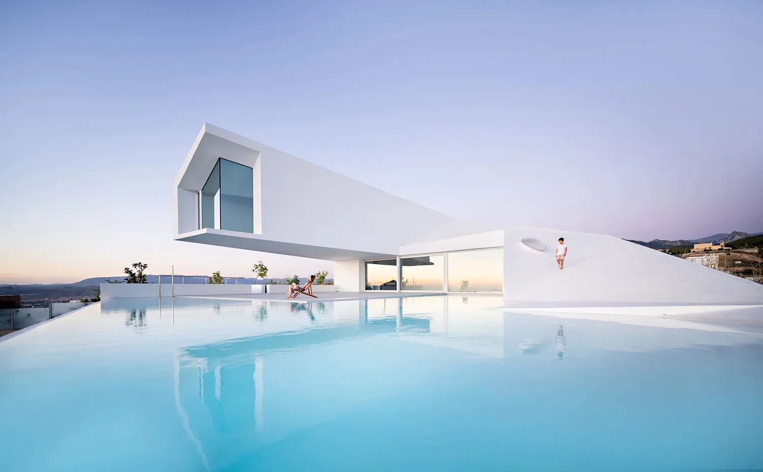 A white minimalist house with a modern architectural design, featuring a large swimming pool and creating a serene, modern at