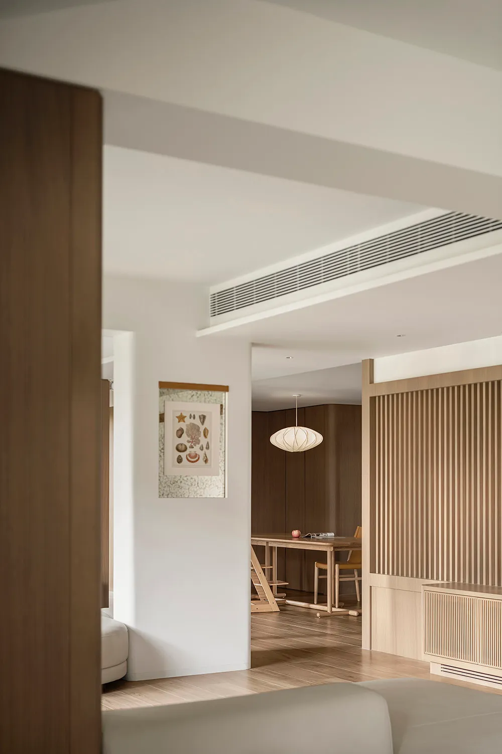 A modern living room with white walls, wooden furniture, and minimalistic decor.