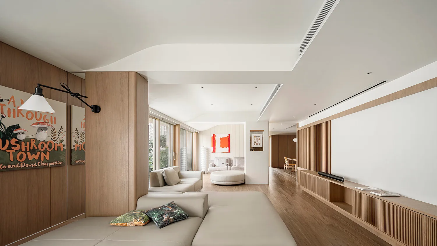 Modern living room interior featuring a beige sofa with cushions, a white ottoman, and a wooden floor with integrated ceiling