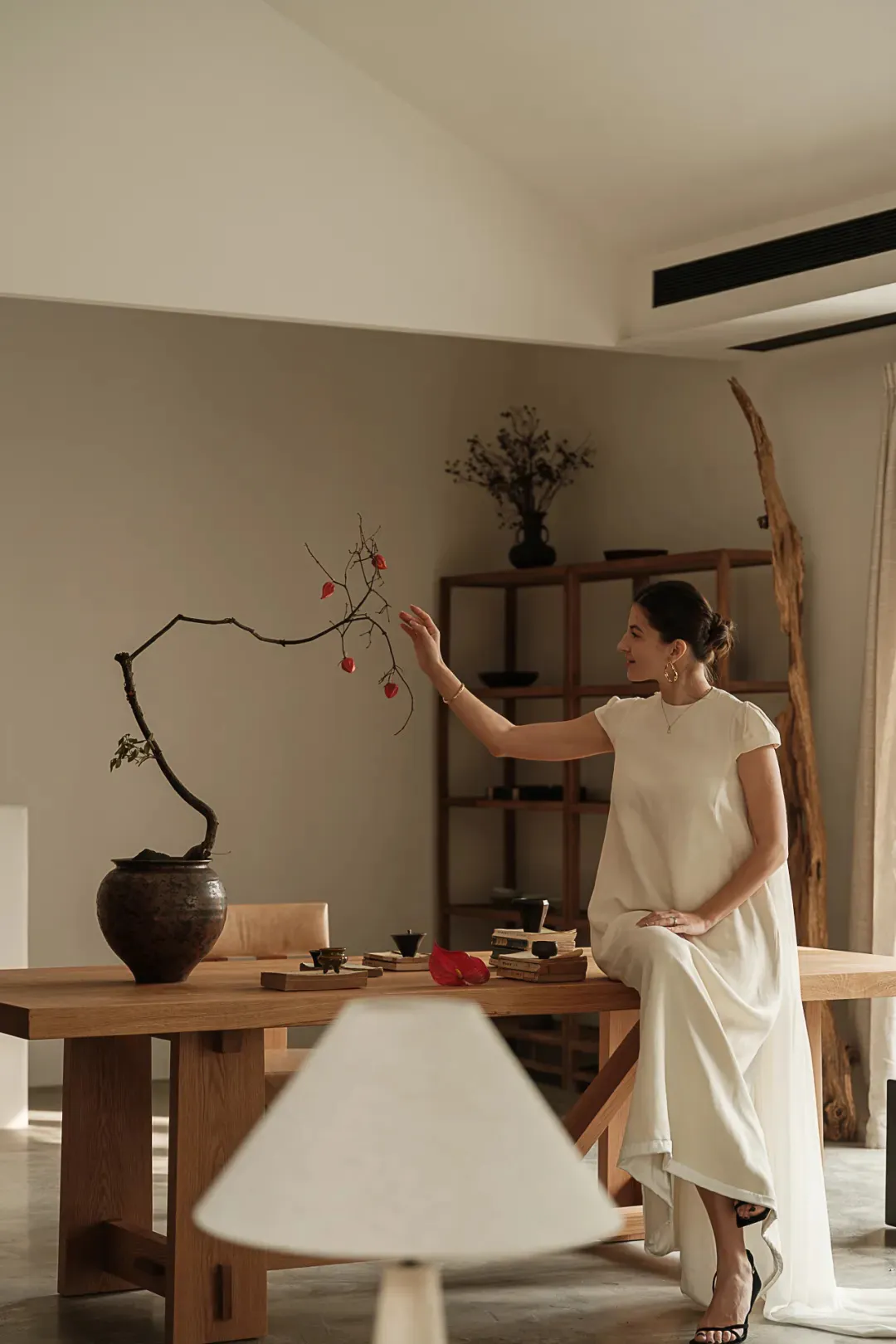 A woman sitting at a wooden table arranging floral decorations.