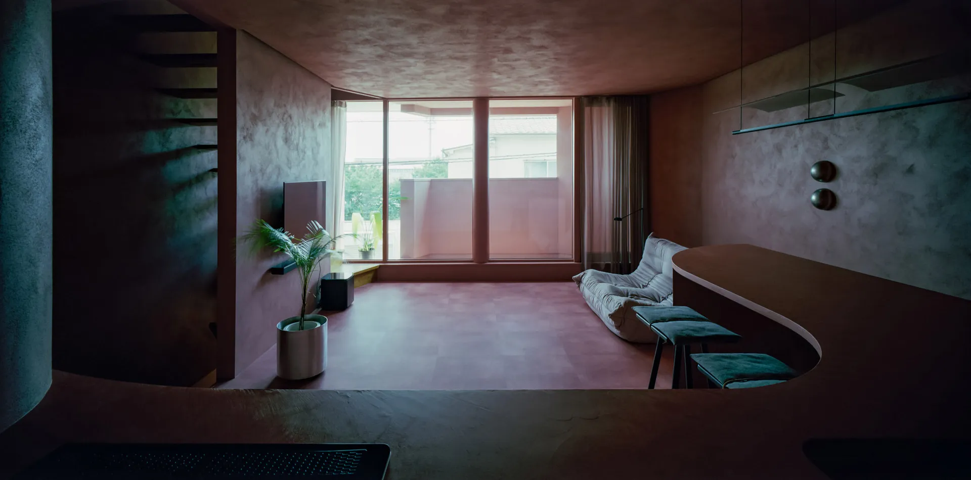 A modern living room with concrete flooring and walls, featuring a lounge area and a bar counter.