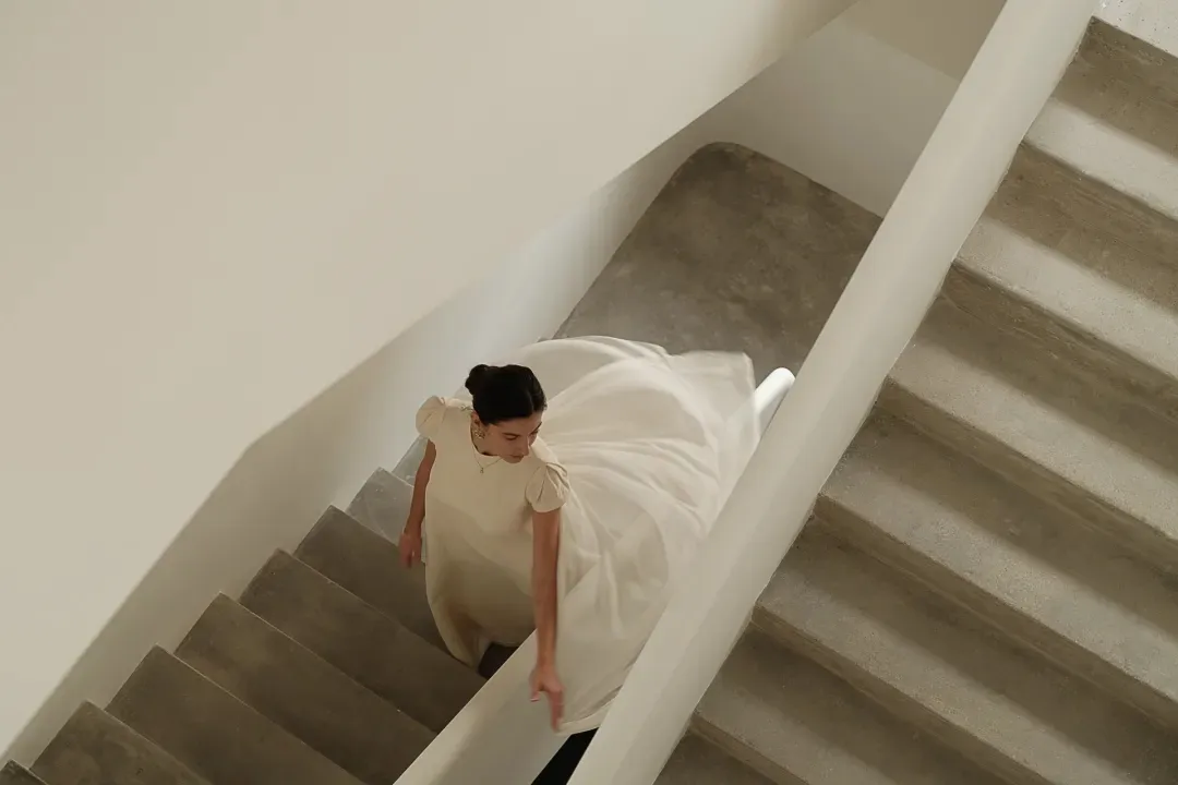 一位身穿白裙的女子正走下樓梯。