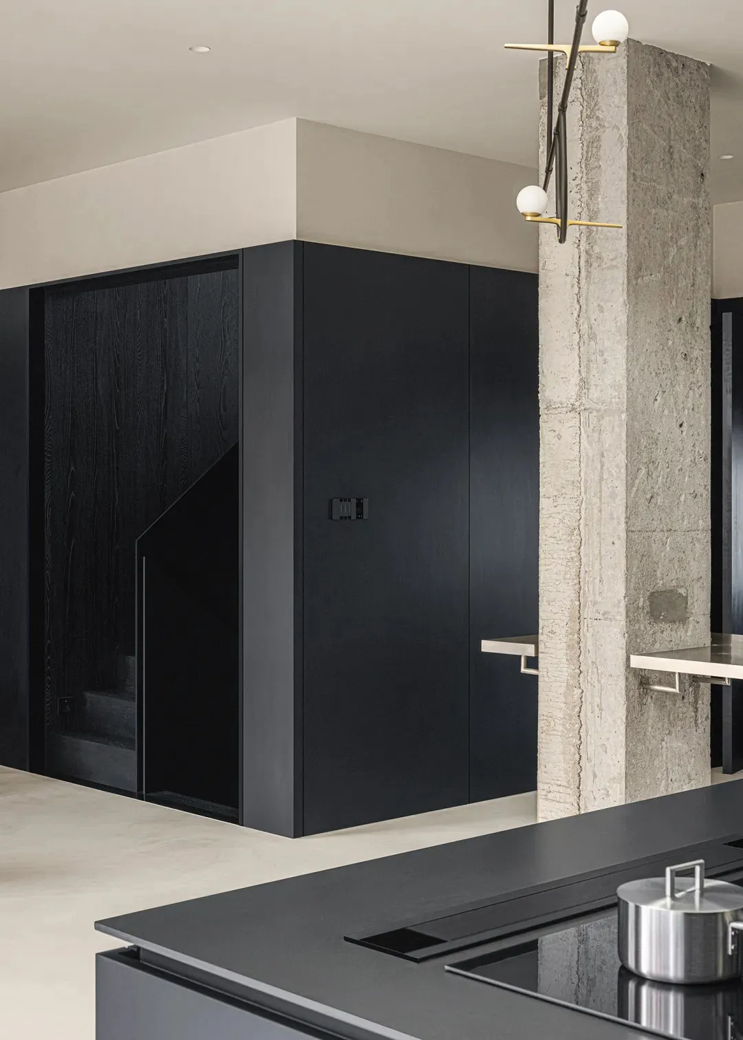 A modern kitchen with black wooden cabinetry and a concrete wall.