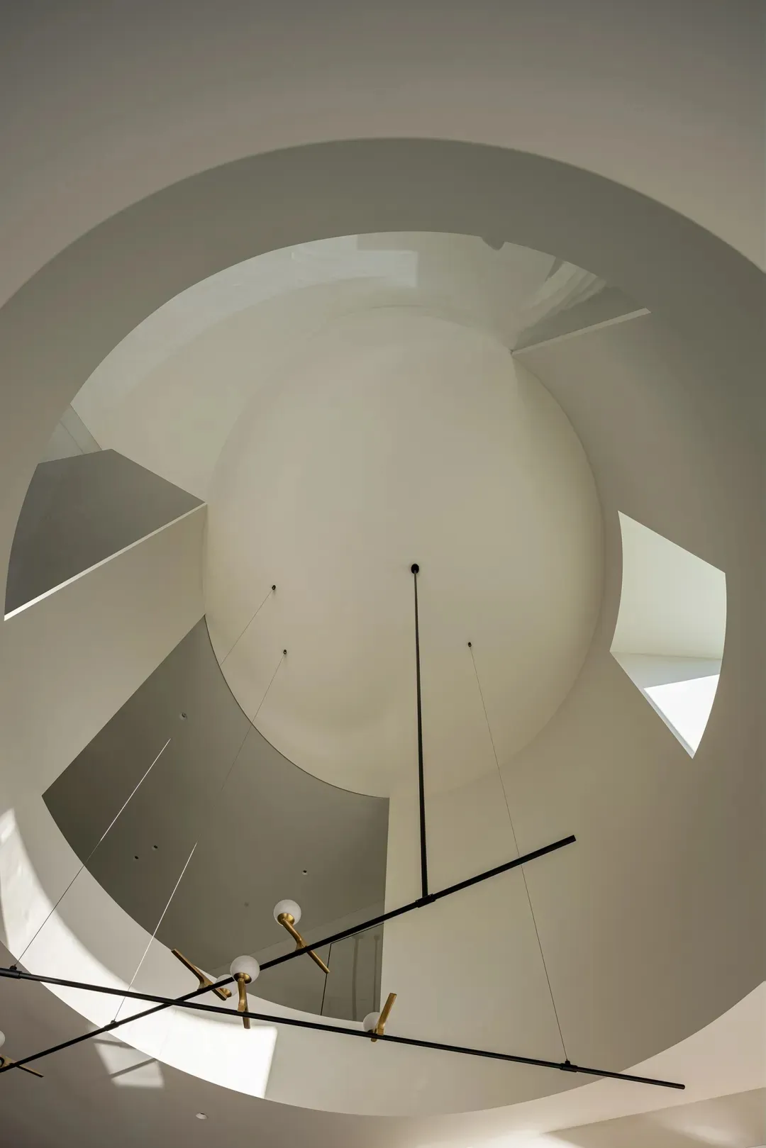 A modern circular ceiling light fixture hanging from a high ceiling.
