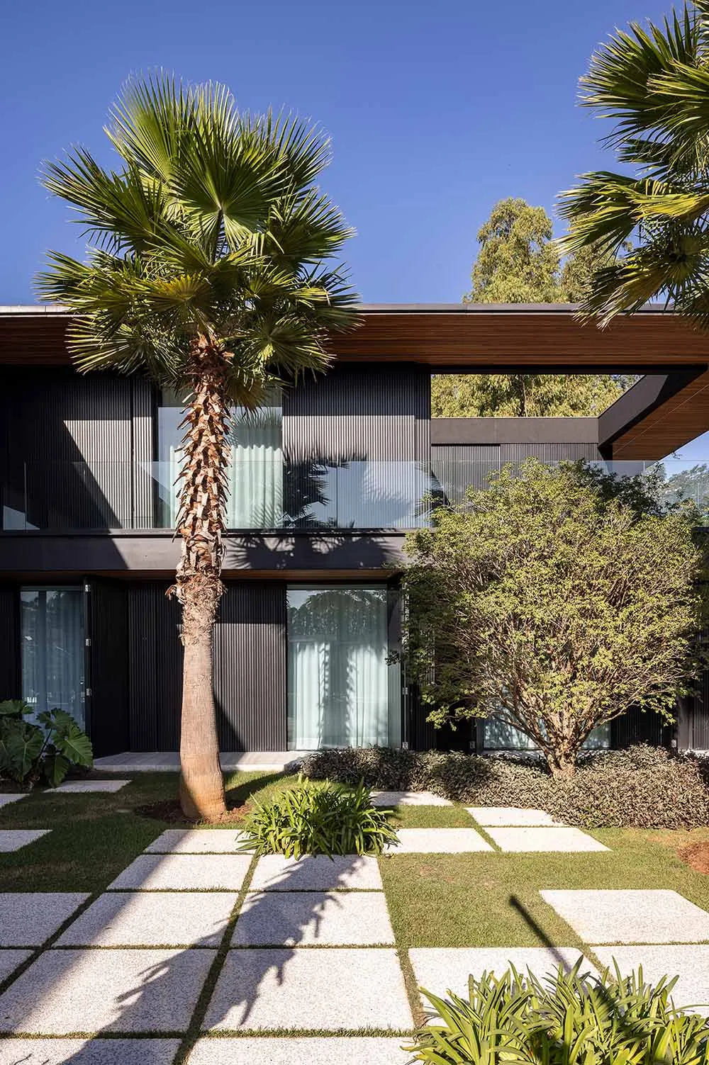 Modern house exterior with metal cladding, glass windows, and concrete patio.