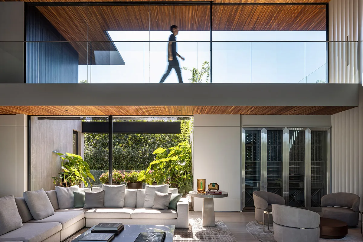 Modern living room with a white sectional sofa, glass coffee table, and green plants