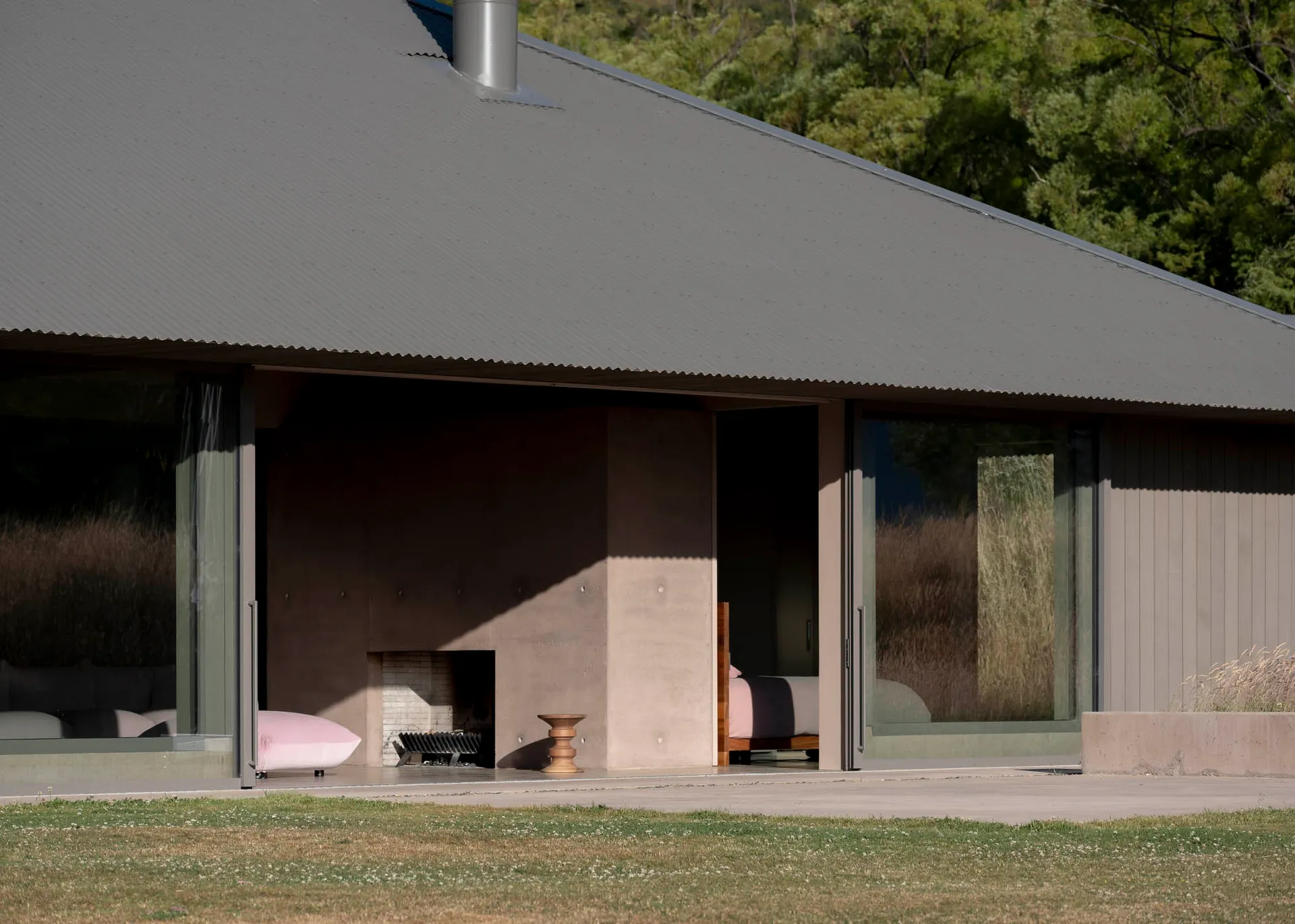 A modern minimalist house featuring a concrete exterior with large glass windows and a flat roof.