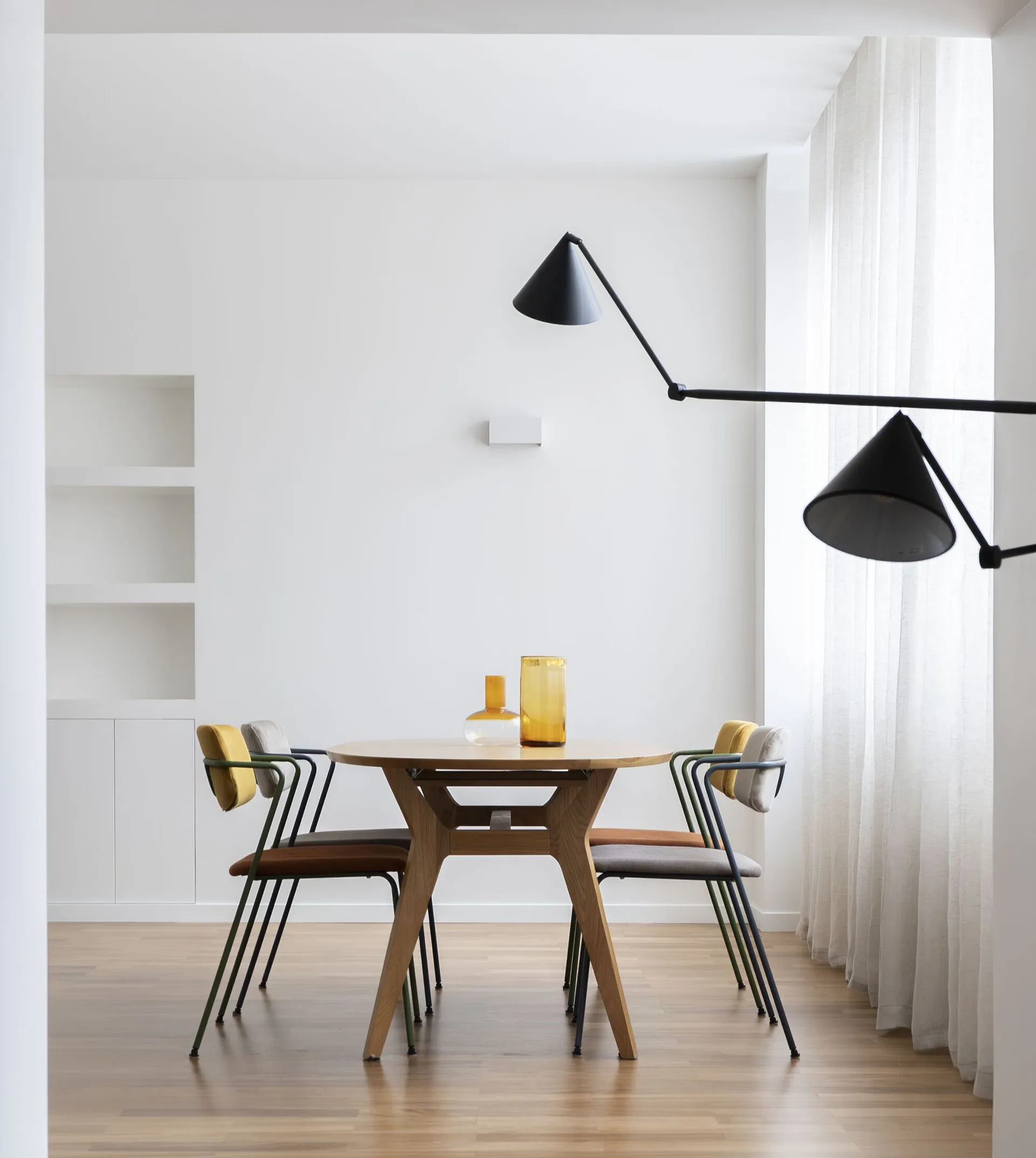 Minimalist dining room with wooden furniture and modern lighting fixtures.