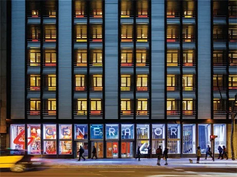 Modern building facade featuring illuminated glass windows and concrete columns.