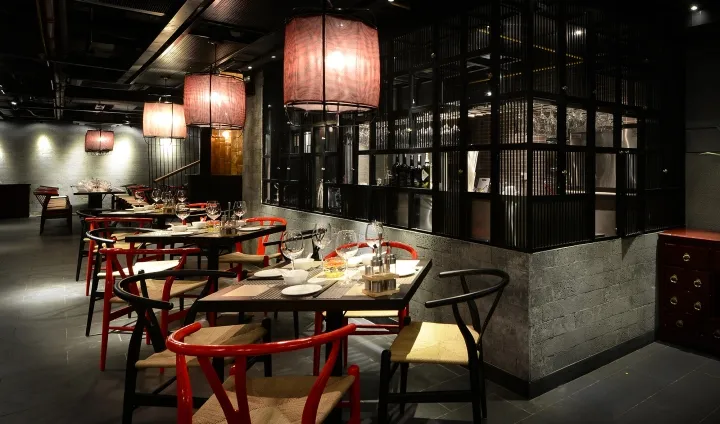一間當代餐廳，配有紅黑家具、木製餐椅與混凝土牆面。