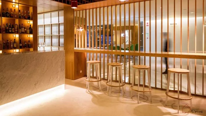 A modern, industrial-style restaurant bar with wooden stools and a wooden divider.