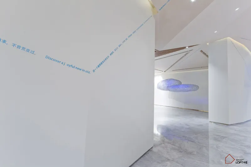 A minimalist interior design featuring a modern art installation with floating metallic cloud shapes illuminated upon suspend