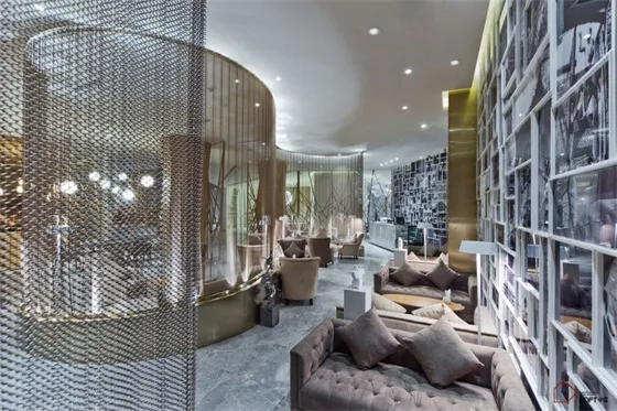 Modern hotel lounge with metal chain curtains, glass tables, and plush seating.