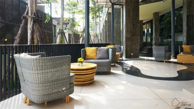 A modern lobby with concrete and glass materials, featuring contemporary seating arrangements and natural light.