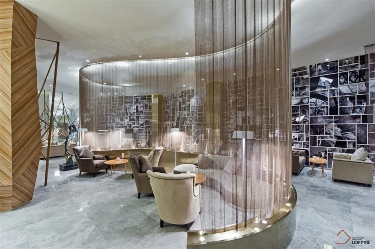 Contemporary lobby area with a metal-netting wall, marble floor, and modern furniture.