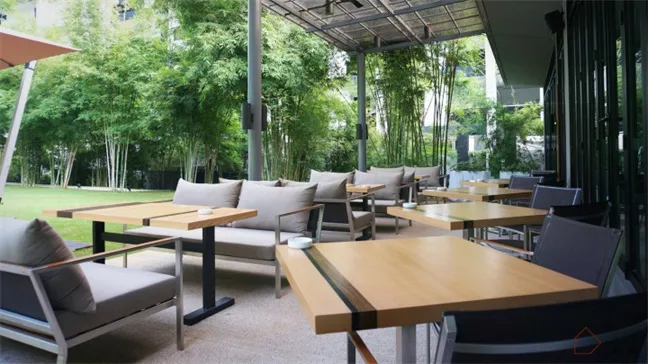 現代戶外餐廳露台,木質餐桌搭配金屬椅,四周環繞綠意與竹子