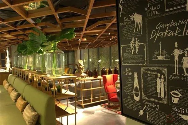 Modern restaurant interior with green seating, wooden accents, and chalkboard wall.