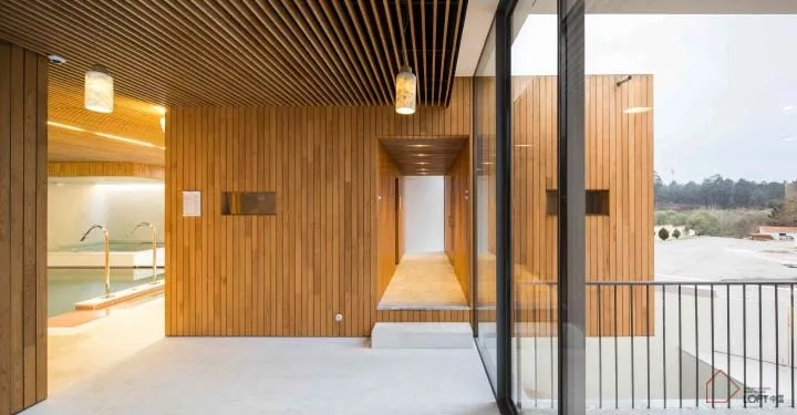 現代度假屋室內,木質牆面與地板、大型窗戶,以及可俯瞰風景的陽台。