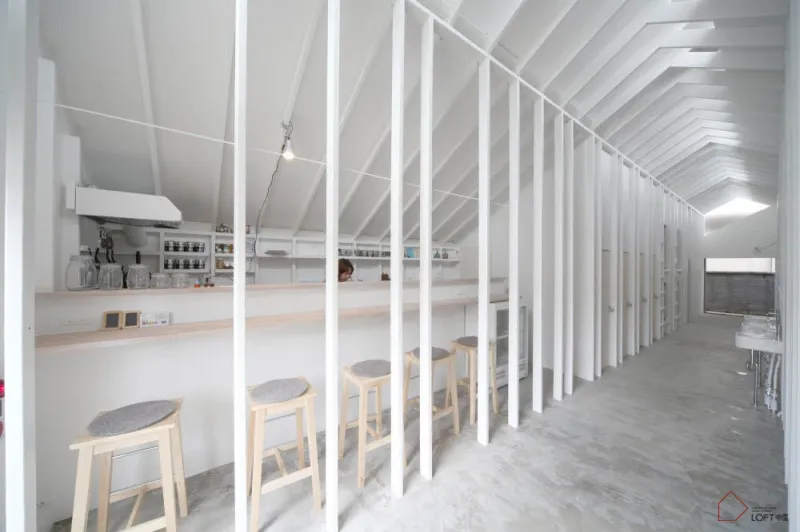 A minimalist cafe bar interior with concrete floors and white walls.
