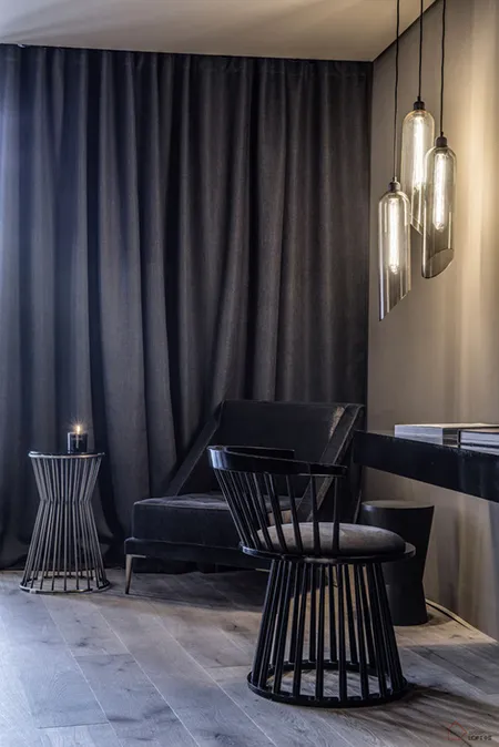 A modern living room featuring black furniture and glass pendant lights.