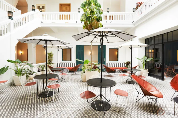 A modern industrial cafe featuring metal furniture and a geometric checkered tile floor.