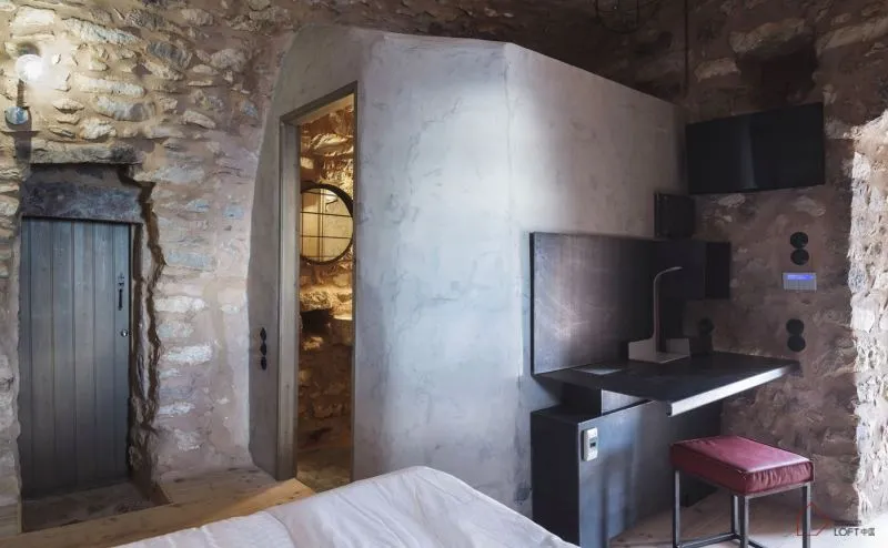 A minimalist bathroom with concrete walls and a white bed.