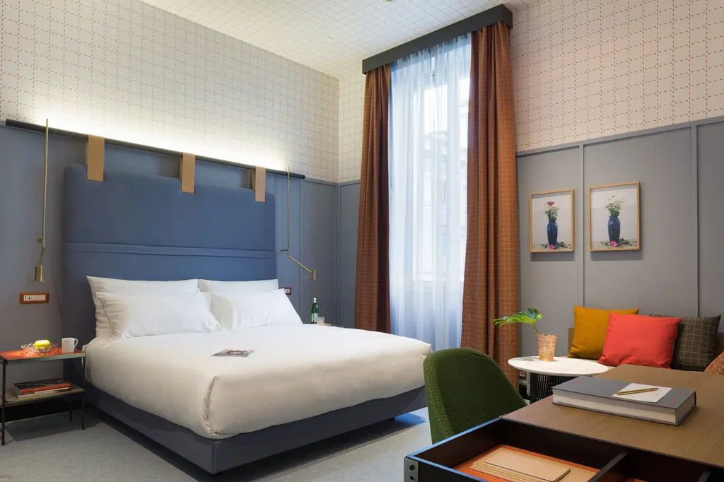 Modern bedroom with a blue upholstered headboard and cotton-blend bedding.