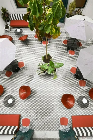 A modern café with tile floors, red accent chairs, and potted plants.