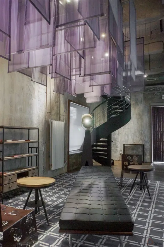 Indoor space featuring modern industrial design elements including metal, fabric, concrete, and glass.