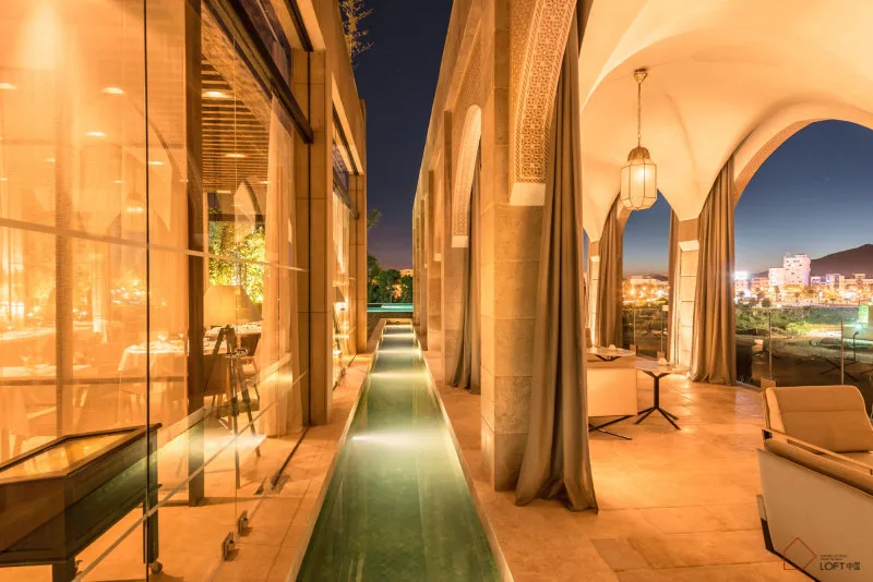 Modern residential exterior with glass terraces and lanterns at dusk, overlooking city lights.