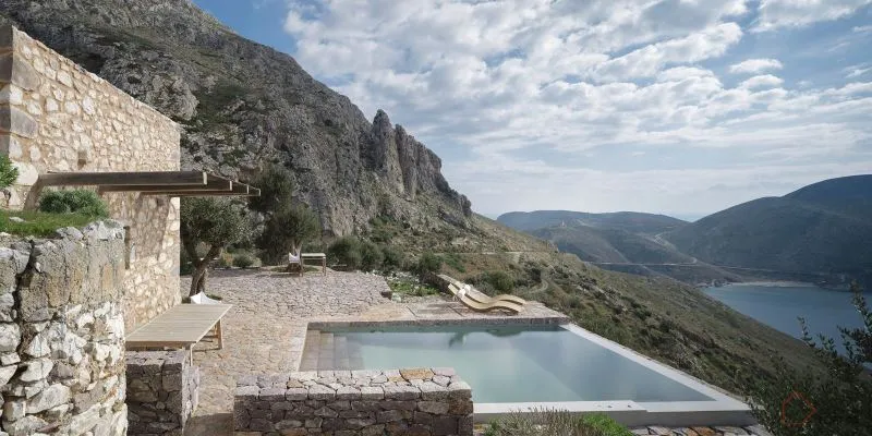 A modern residential landscape featuring a swimming pool with a stone patio and mountainous backdrop.