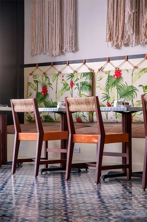 A photograph of a restaurant interior featuring textured striped polyester canvas walls, wooden chairs with orange cushions,