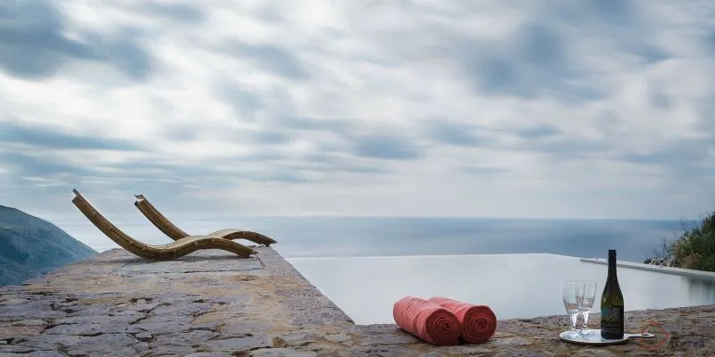 Vacation home with stone exterior, infinity pool, and sea view.