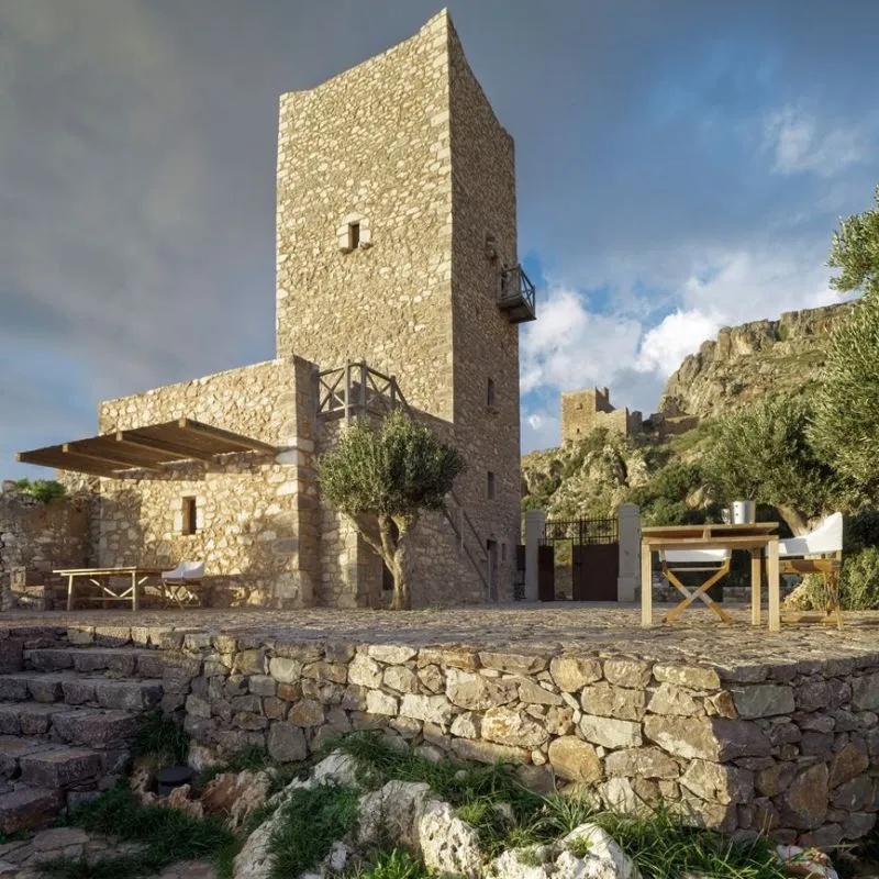 A stone building with a tower and outdoor seating area.